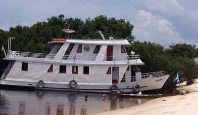 A traditional Amazon cruise boat moored beside the forest