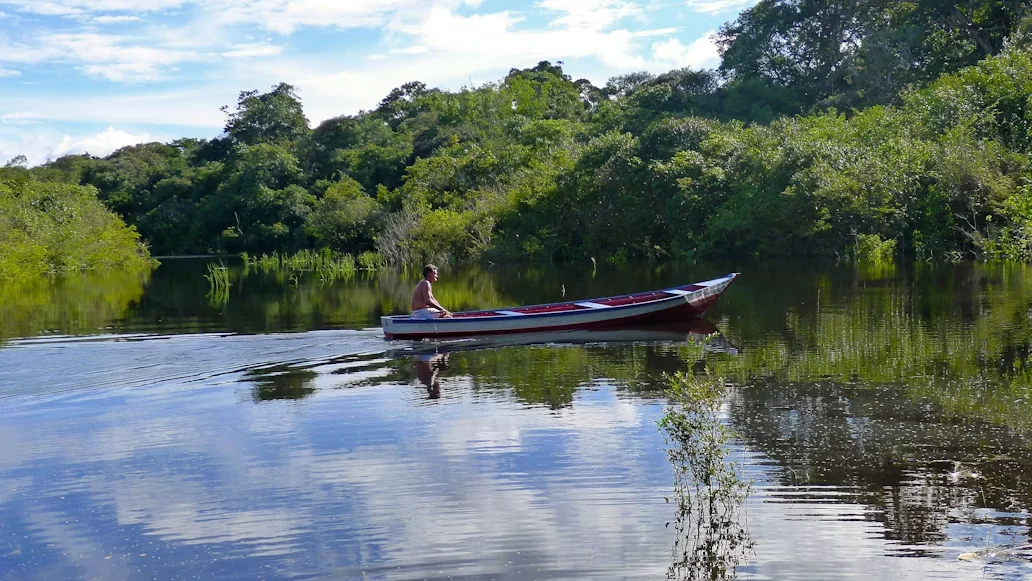 A local canoe crossing a calm Amazon waterway near Manaus