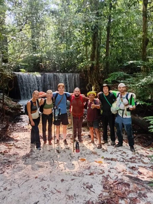 Travellers reaching a forest waterfall on a remote journey